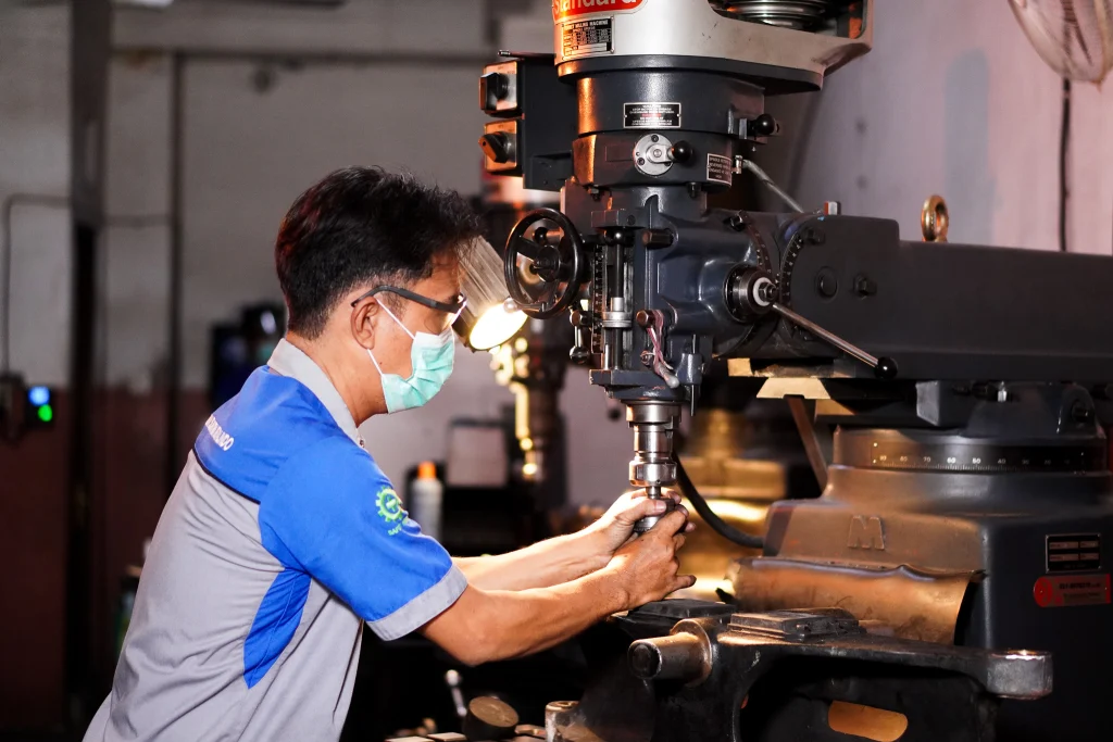 Teknisi mengoperasikan mesin milling saat fabrikasi komponen piping gas industri